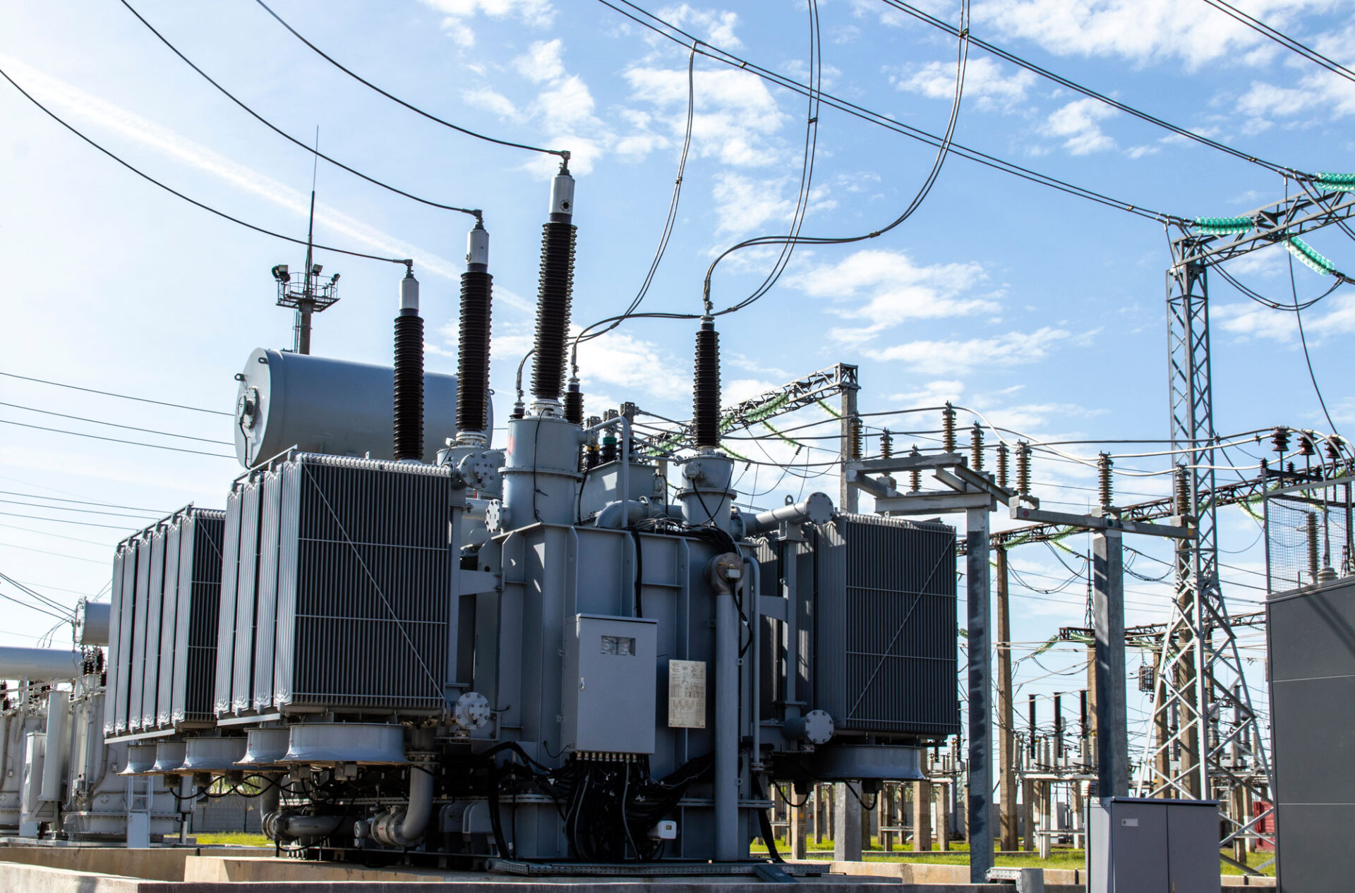 An expansive view of an electrical substation featuring large transformers and intricate high-voltage lines, indicating a complex and well-established power distribution network.